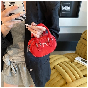 Detailansicht der roten Mini-Handtasche aus Leder mit silberner Schleife und Model