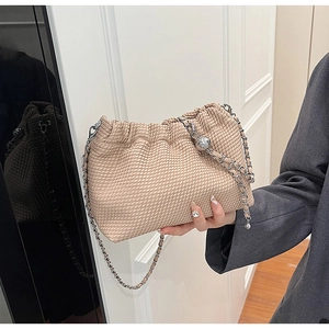 Detail of beige woven cloud bag with silver chain strap and decorative metal sphere accent