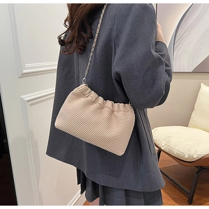 Detailed shot of beige quilted faux leather shoulder bag with gold chain strap worn by model