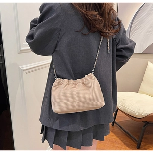 Close-up of beige waffle texture handbag with silver chain strap and minimalist design