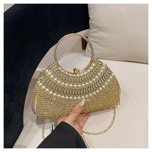Detailed shot of luxurious gold evening bag with pearls, crystals and round metal handle