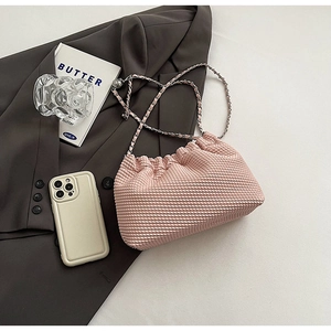 Detail of pink pleated texture shoulder bag with elegant silver chain strap on suit