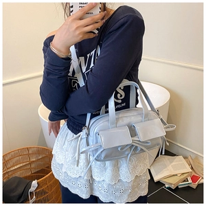 Detail of light blue glossy leather handbag with bow accents and dual front pockets