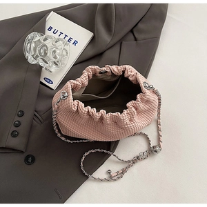 Detail of light pink pleated cloud bag with silver chain strap and gray interior lining