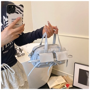 Detail of light blue patent leather handbag with bow accents and twin flap pockets