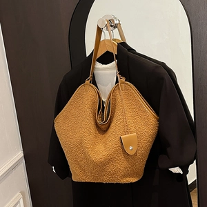 Detail of teddy fleece tote bag with brown leather trim and drop-shaped charm