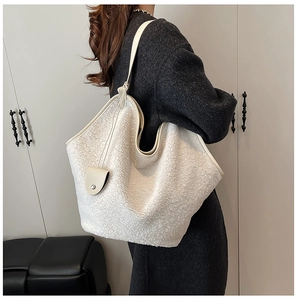 Detail of soft cream faux shearling tote bag texture and leather charm on shoulder bag