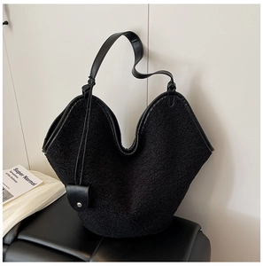Detail of black fuzzy tote bag featuring faux shearling texture and leather pouch strap