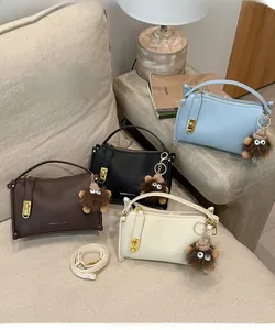 Detailed close-up of litchi grain faux leather handbag with monster charm and metal lock