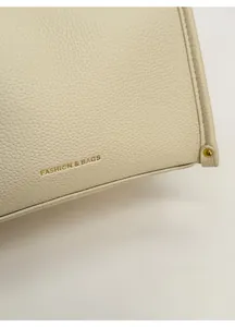 Macro shot of cream lychee texture leather detail with gold FASHION & BAGS lettering