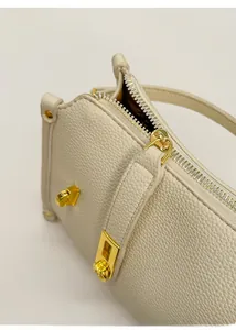 Detail of lychee pattern leather handbag with gold metal zipper and refined stitching