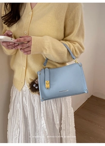 Detail of light blue lychee texture leather handbag with gold rivets and monster charm