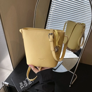 Yellow bucket shoulder bag with lychee texture and heart pendant in lifestyle setting
