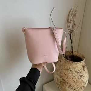 Pink lychee grain leather bucket bag with adjustable strap and minimalist design