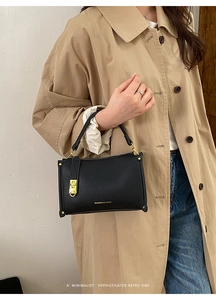 Detail of black lychee grain leather handbag with gold hardware and fashion logo