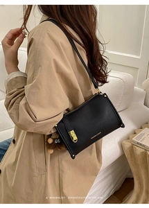 Detail of black crossbody bag featuring gold hardware and a cute plush doll charm