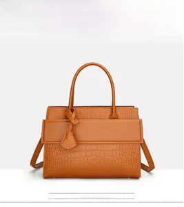 Detailed view of brown crocodile embossed texture and metal logo on women's handbag