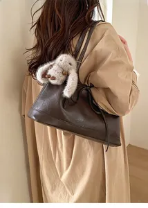 Detail of dark brown leather shoulder bag with a cute plush rabbit charm