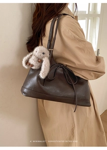 Detail of dark brown faux leather tote with decorative bow and plush bunny pendant