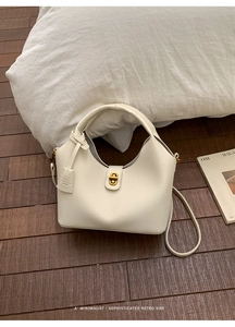 Nahaufnahme der cremefarbenen Eimer-Tasche aus Leder mit Goldverschluss und Schultergurt