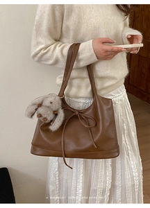 Detail of retro brown shoulder bag with bow drawstring and cute plush bunny charm