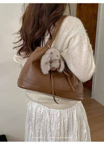Detail of retro brown faux leather shoulder bag with a cute plush rabbit pendant charm