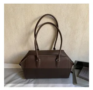 Detail of dark brown pebble leather bowling bag with long shoulder straps and silver rings