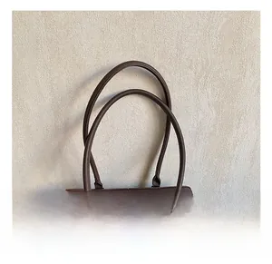 Detail of dark brown lychee grain leather handbag handles and precise stitching
