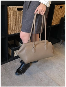 Detail of taupe leather bowling bag showing soft lychee texture and long handle strap