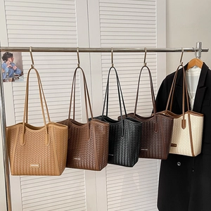 Detailed display of assorted large capacity woven tote bags hanging on a display stand