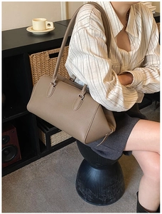 Detailed texture of taupe lychee grain leather Boston bag with long handles and zipper