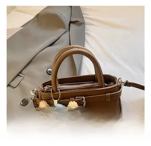 Detailed view of brown litchi grain leather tote bag with cute plush bear charm accessory