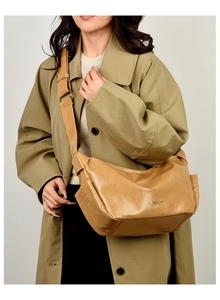 Caramel pleated PU leather crossbody bag worn with olive green coat in a minimal setting