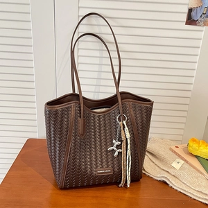 Detail of dark brown woven tote bag featuring silver balloon dog charm and brand logo