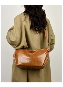 Rear view of model wearing a vintage brown wrinkled leather crossbody bag over a trench coat