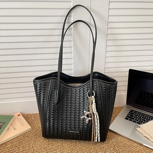 Detail of black woven leather tote bag with silver balloon dog and fringe accessories
