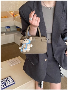 Detail of khaki leather tote bag with metal buckle and cute teddy bear charm pendant