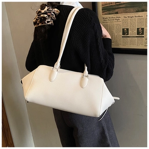 Side view of white textured leather bowling bag worn by a model in casual style