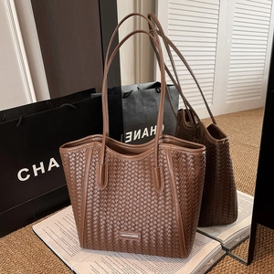 Detailed woven texture of a large brown faux leather tote bag with slim shoulder straps