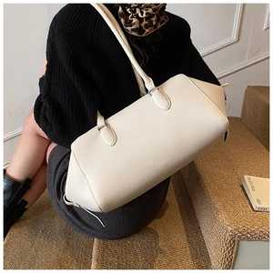 Detailed view of beige lychee texture leather bowling bag worn as an underarm shoulder bag