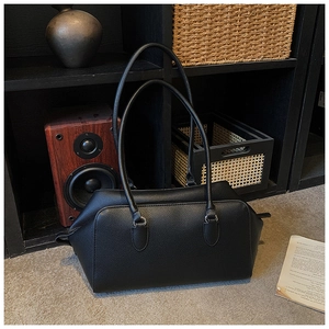Detail of black lychee grain leather tote bag with silver metal ring and thin handles