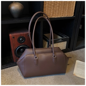 Close-up of deep brown lychee grain leather tote bag with long handles on a grey rug