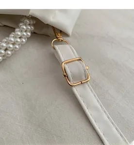 Detail of white lychee leather texture with pearl handle and golden buckle