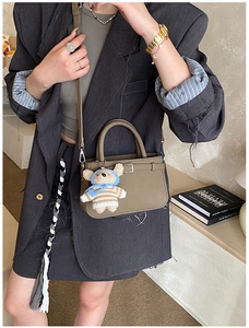 Olive green tote bag with cute plush bear pendant shown on model in stylish interior
