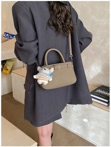 Khaki pebbled leather tote bag with a cute teddy bear charm shown on a crossbody model