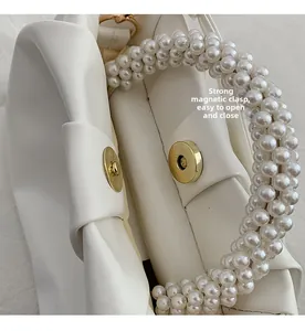 Detail of white pleated cloud bag showing strong magnetic closure and golden clasp