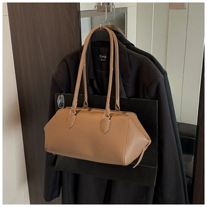 Detailed texture of brown pebble leather shoulder bag on a dark wool coat background
