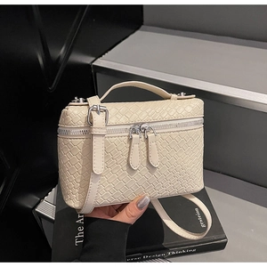 Detalle de mini bolso bandolera trenzado en color crema con asa y herrajes plata