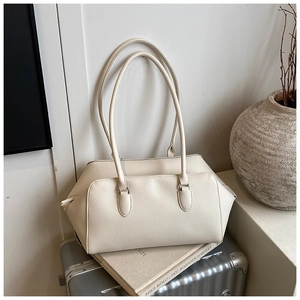 Close-up of off-white lychee grain leather tote bag with long handles on a vintage suitcase