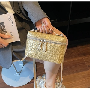Detalle de bolso dorado metalizado con textura trenzada y cremallera doble